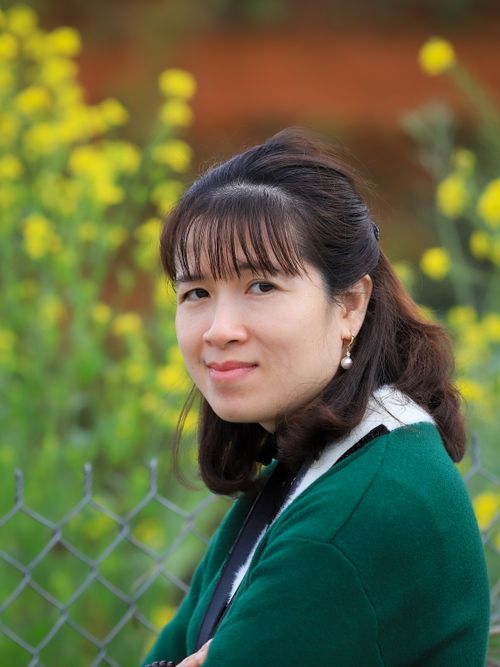 Free Portrait of a woman outdoors in Lào Cai, Vietnam with yellow flowers in the background. Stock Photo