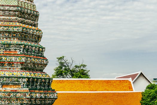 Low angle view of Wat Arun's intricate architecture in Bangkok, showcasing vibrant colors and detailed craftsmanship.