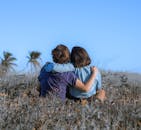 一对夫妇坐在草地上，在晴朗的蓝天下相拥