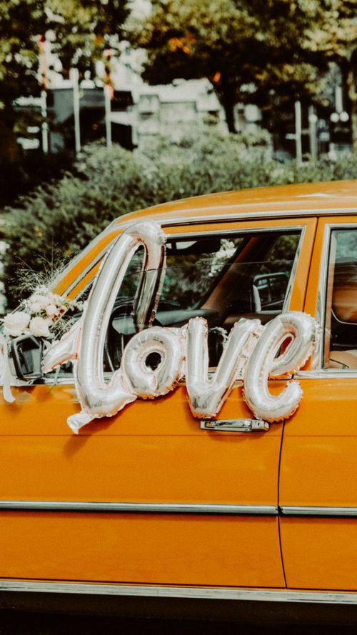 Free Vintage yellow car decorated with love balloons and flowers. Perfect for wedding or romantic themes. Stock Photo