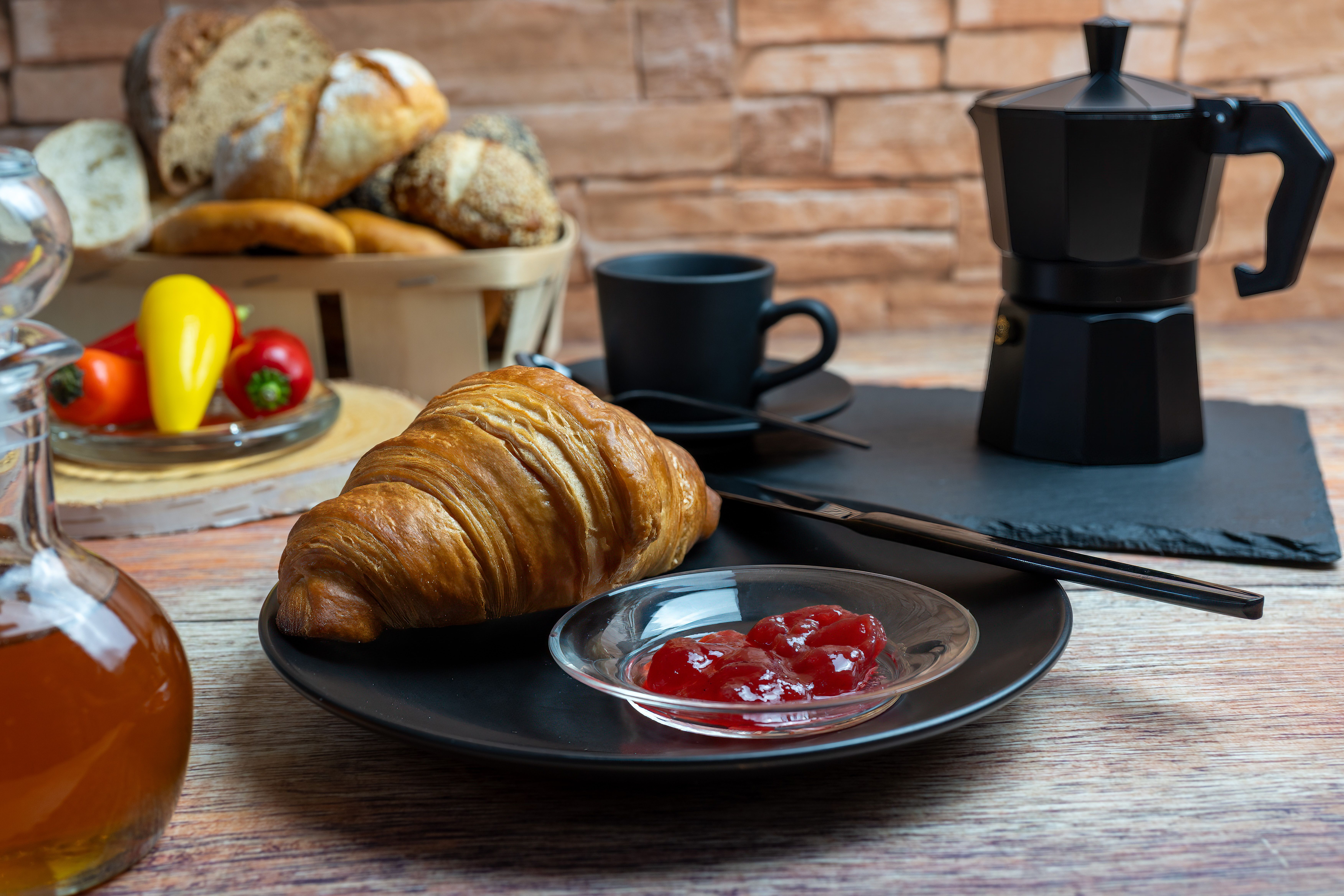 Inviting breakfast setup with a croissant, jam, and coffee in a rustic atmosphere.