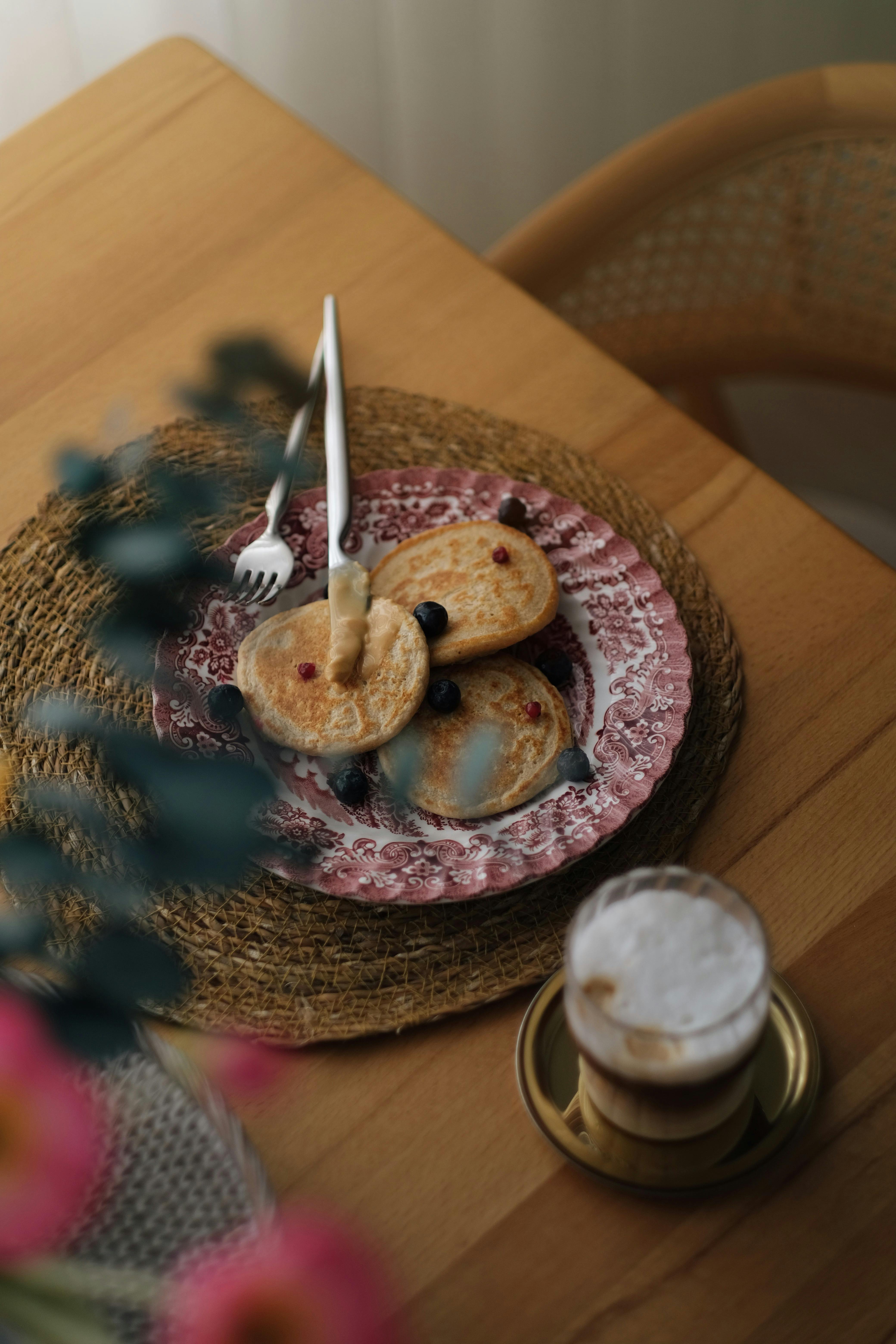 Inviting breakfast scene with pancakes and a coffee on a woven mat.