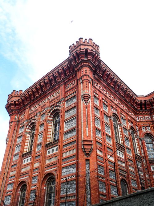 Free A stunning red brick building showcasing gothic architectural details under a clear sky. Stock Photo