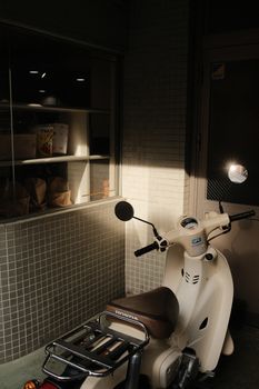 A retro scooter parked outside a stylish café, captured in warm sunlight.