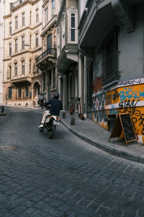Free City street view featuring motorcyclist, graffiti, and historic architecture. Stock Photo