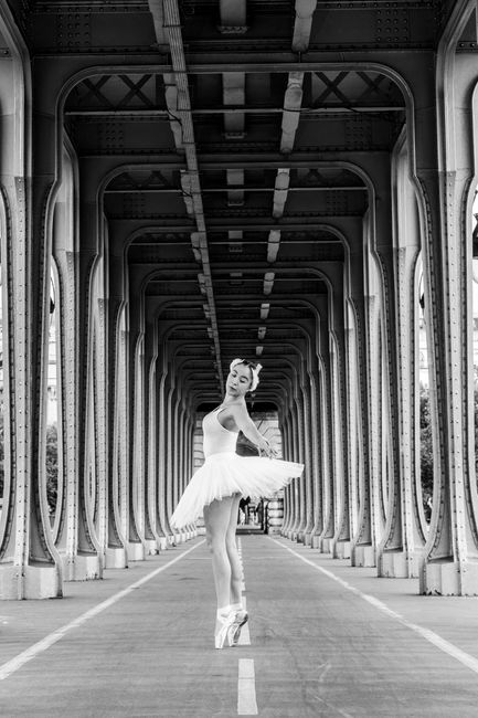 Elegant ballerina dancing under a bridge in Paris, France, showcasing grace and poise.