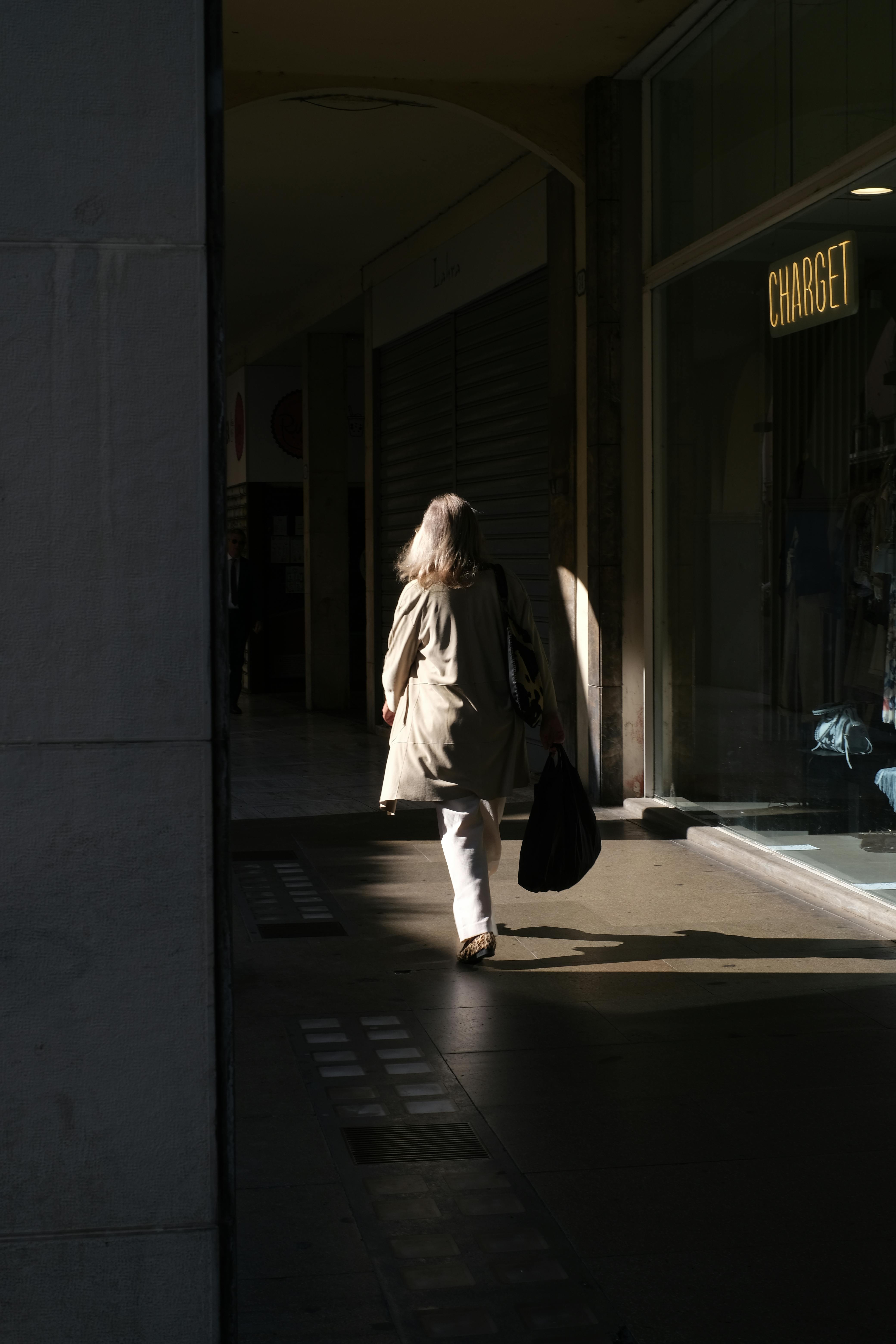 Gratis Una donna con una borsa cammina attraverso un portico ombroso a Padova, Veneto, Italia. Foto a disposizione