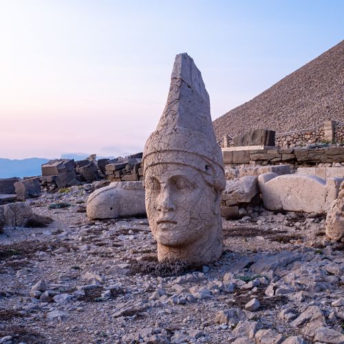 Free Stone head sculpture of a god at Mount Nemrut during sunset, showcasing ancient history. Stock Photo