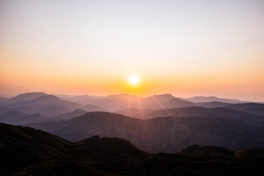 A breathtaking sunrise over layered mountain ranges, offering a serene and awe-inspiring view.