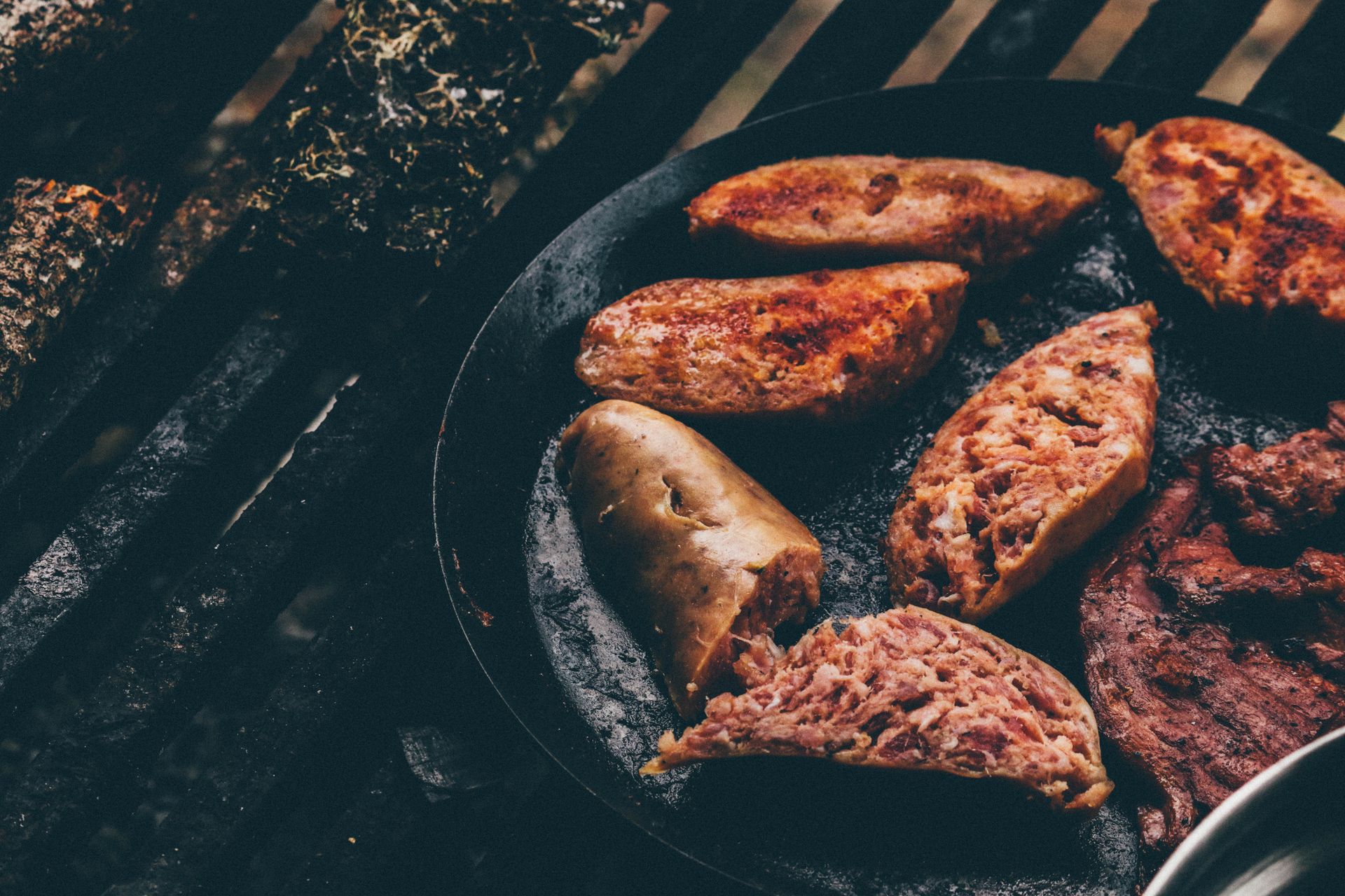 Close-up of sizzling sausages and meat grilling on an outdoor barbecue, exuding a rustic and smoky vibe.