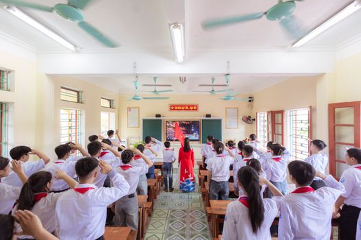 A dynamic classroom scene with students engaged in a collective activity led by a teacher.