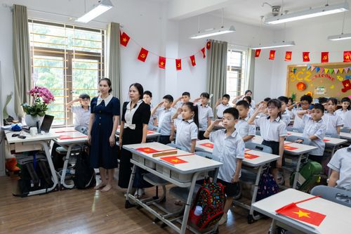 Free Students and teachers in a classroom standing and saluting with flags displayed. Stock Photo