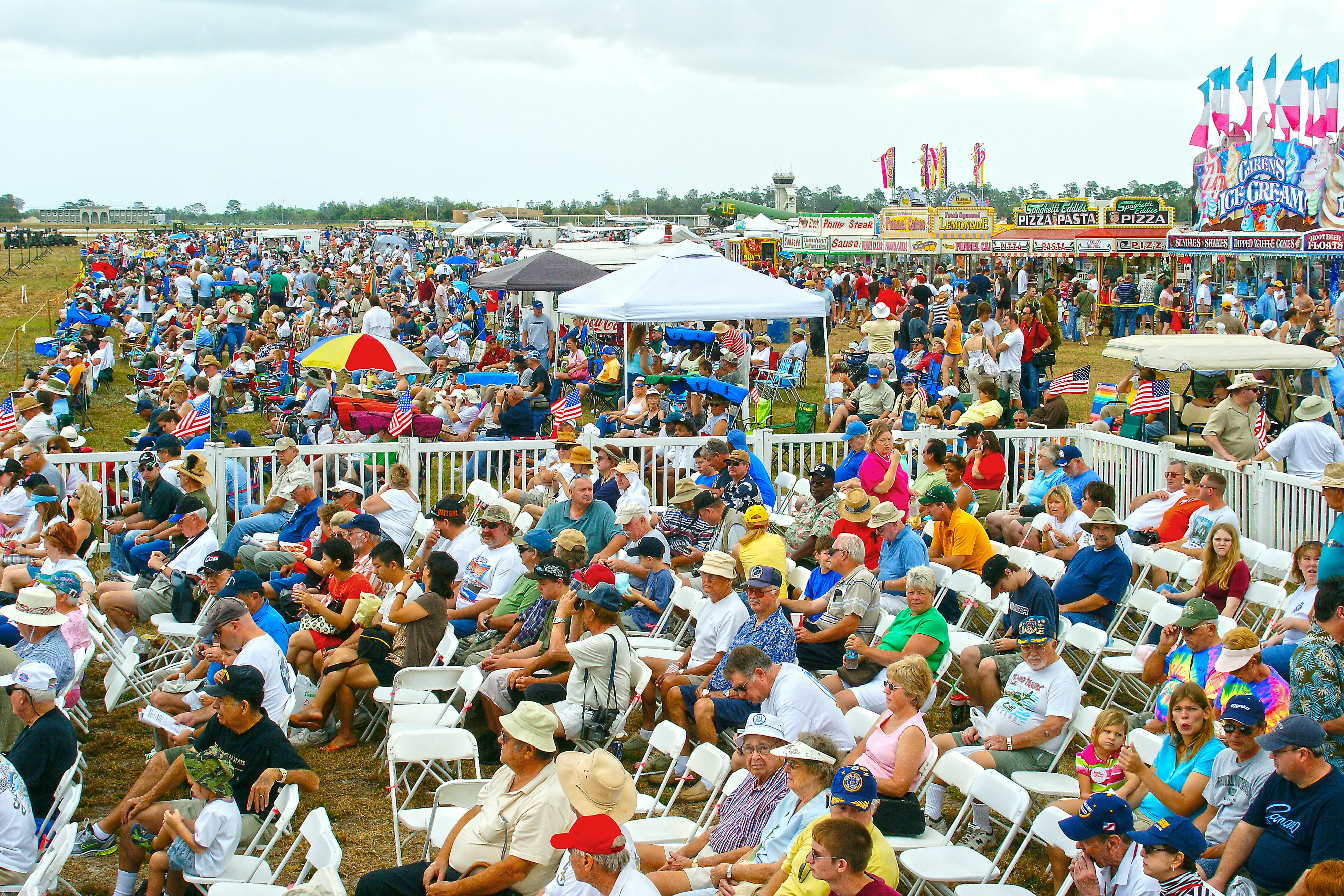 A lively scene of people gathered at an air show in Titusville, Florida, enjoying the festive atmosphere.