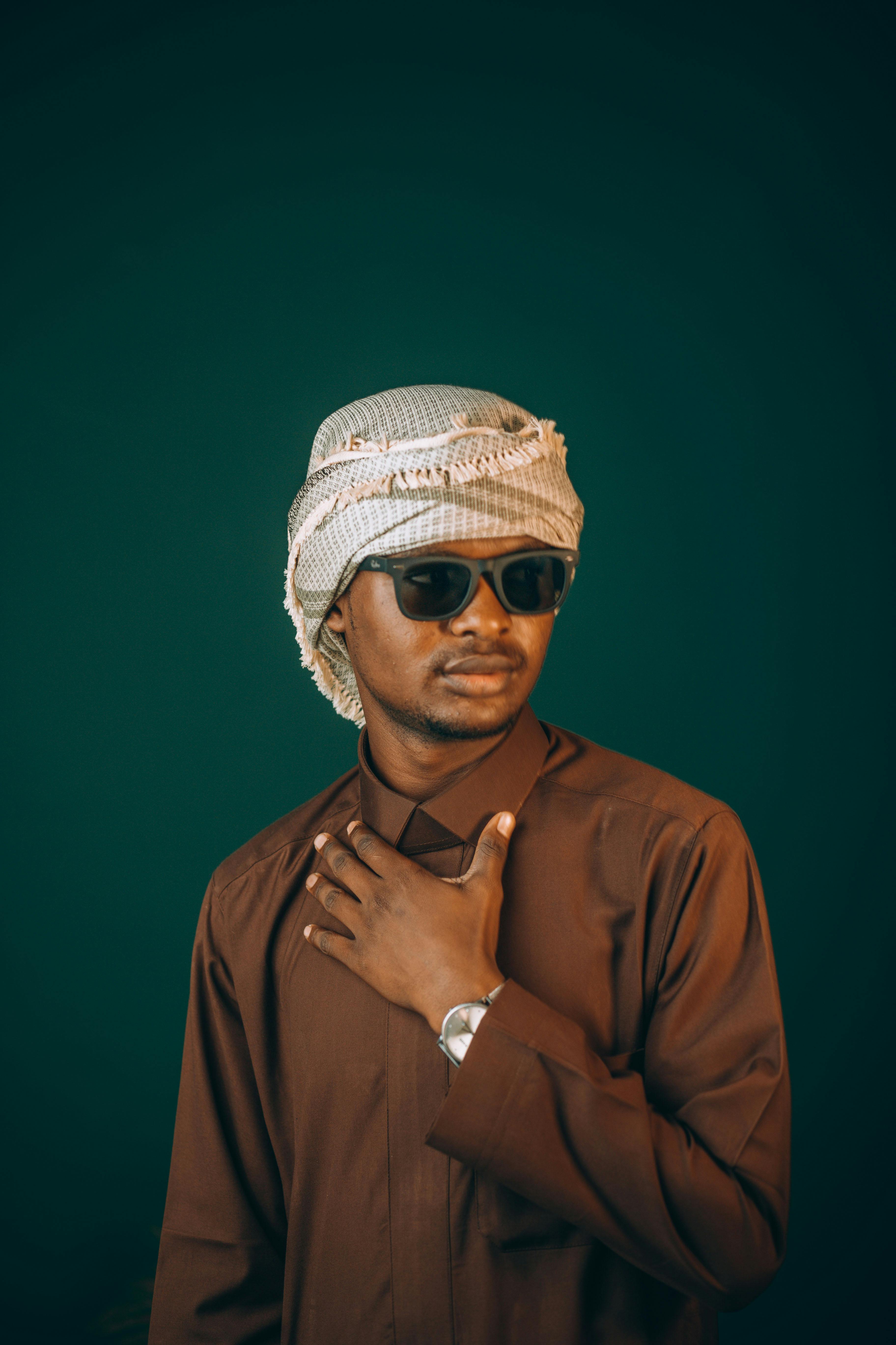 Confident Middle Eastern man in traditional attire and sunglasses posing boldly.