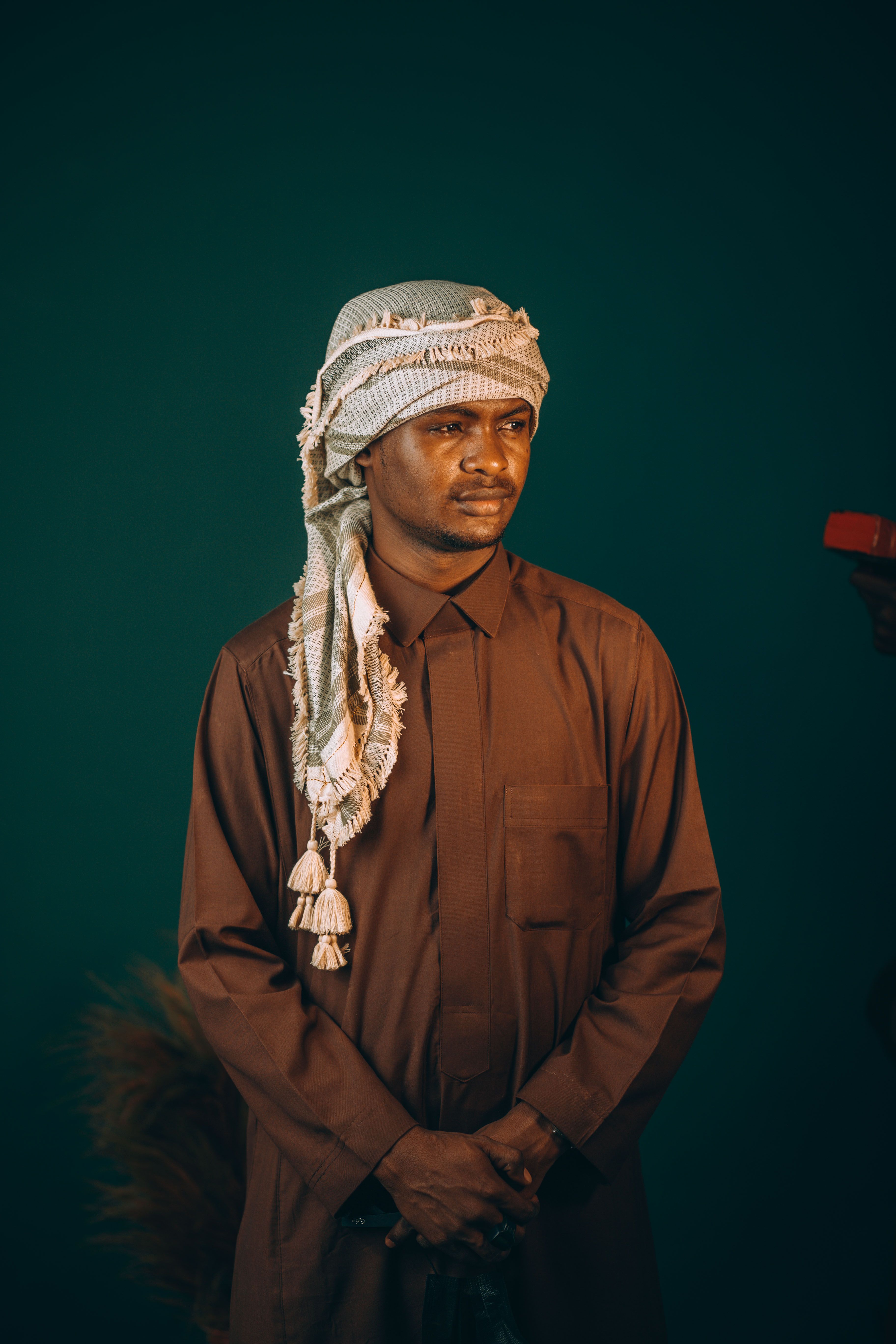 Portrait of a Middle Eastern man in traditional attire, set against a deep green background.