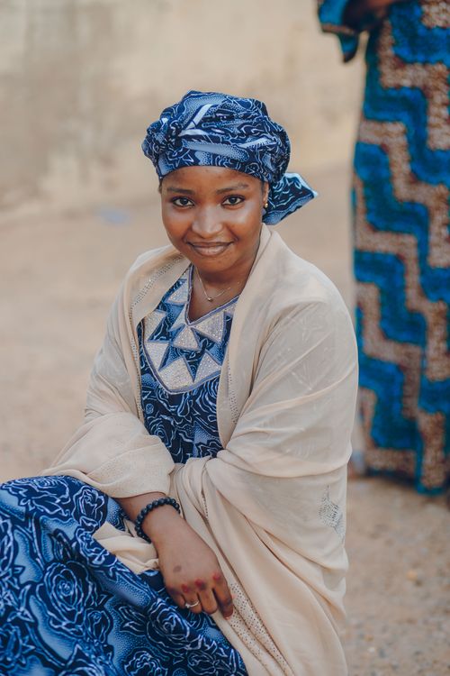 Free An African woman in traditional blue attire smiles warmly outdoors in Nigeria. Stock Photo
