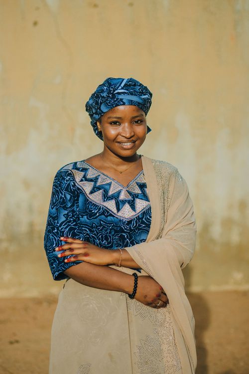 Free A woman in traditional Nigerian attire smiling outdoors against a neutral background. Stock Photo