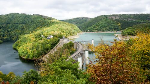 Free Beautiful view of a reservoir and dam surrounded by green hills and colorful autumn foliage. Stock Photo