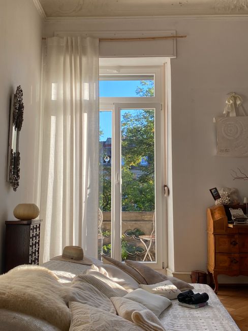 Cozy sunlit bedroom with elegant furnishings and balcony view, perfect for relaxation.