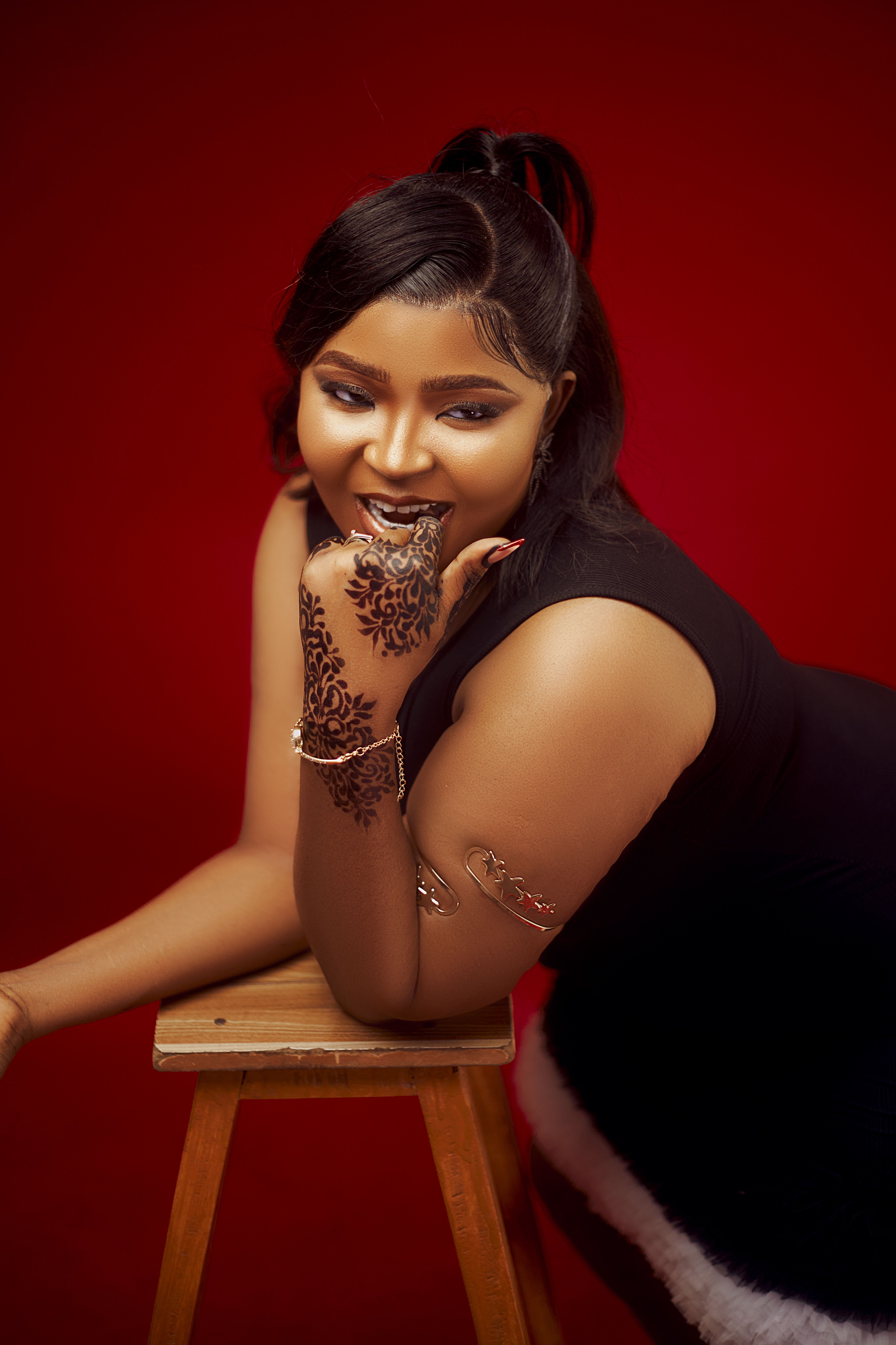 Stylish woman smiling with henna tattoo on hand against red background.