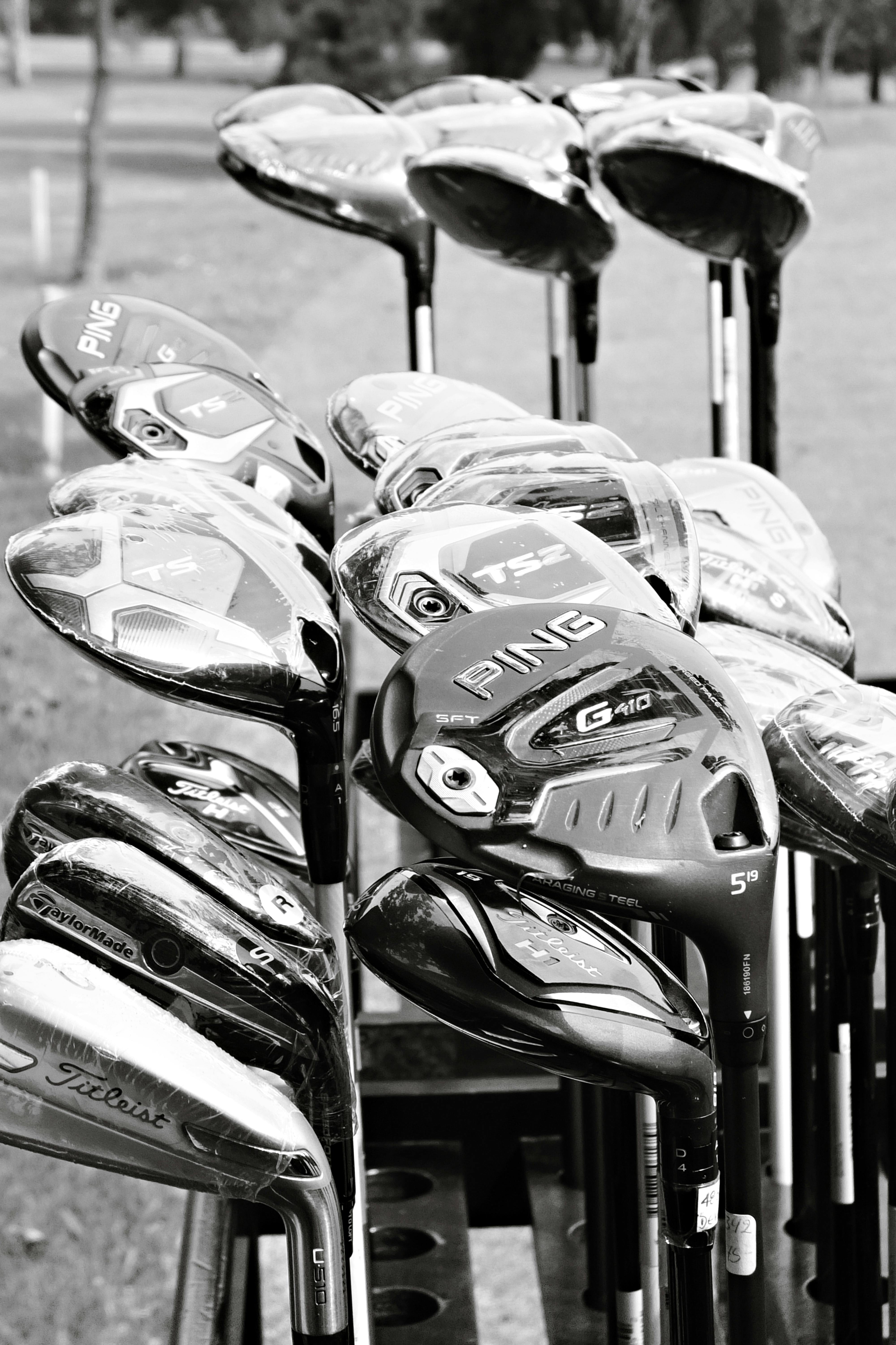 Artistic black and white shot of assorted golf clubs outdoors.
