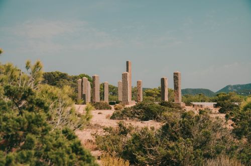 Free Tall stone columns standing in a sunny Mediterranean landscape amidst lush greenery. Stock Photo