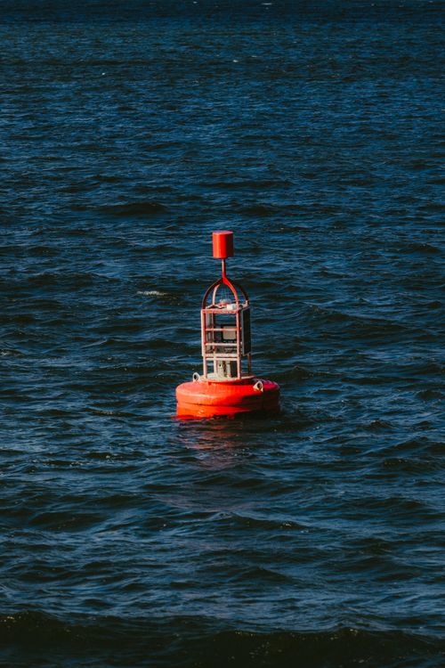Free Vibrant red buoy floating on the deep blue waters of Galway Bay, Ireland. Stock Photo