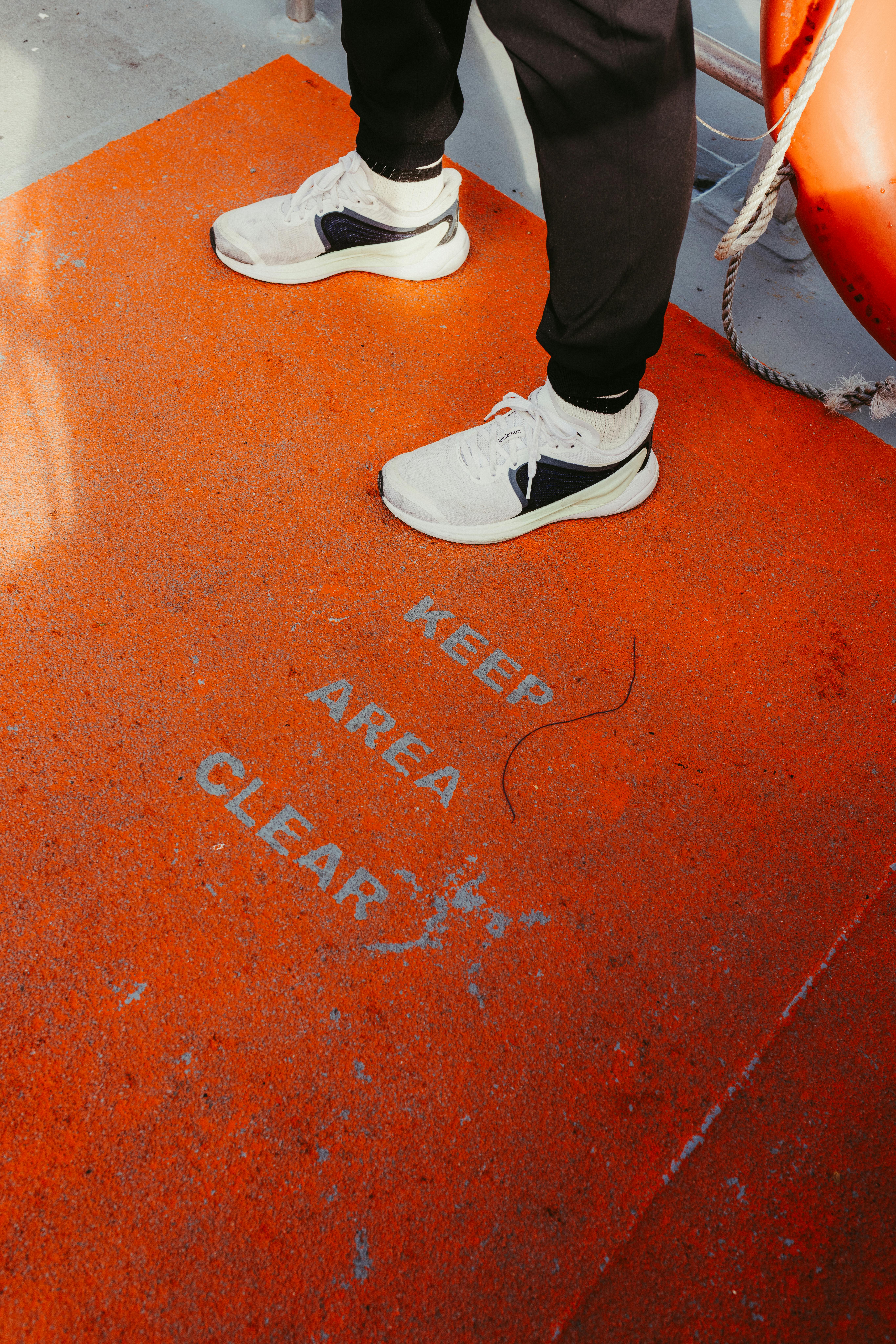 De franc Primer pla d'una persona amb sabatilles esportives en una terrassa taronja amb el rètol "Mantenir la zona neta". Foto d'estoc