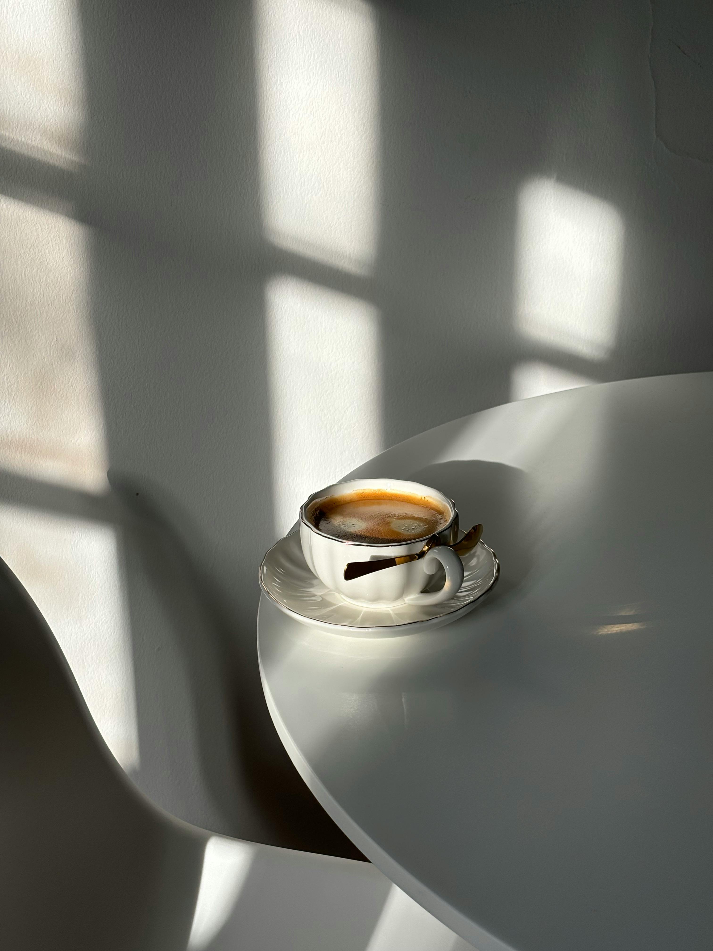 Gratis Taza De Café Artística Sobre Una Mesa Iluminada Por El Sol Foto de stock