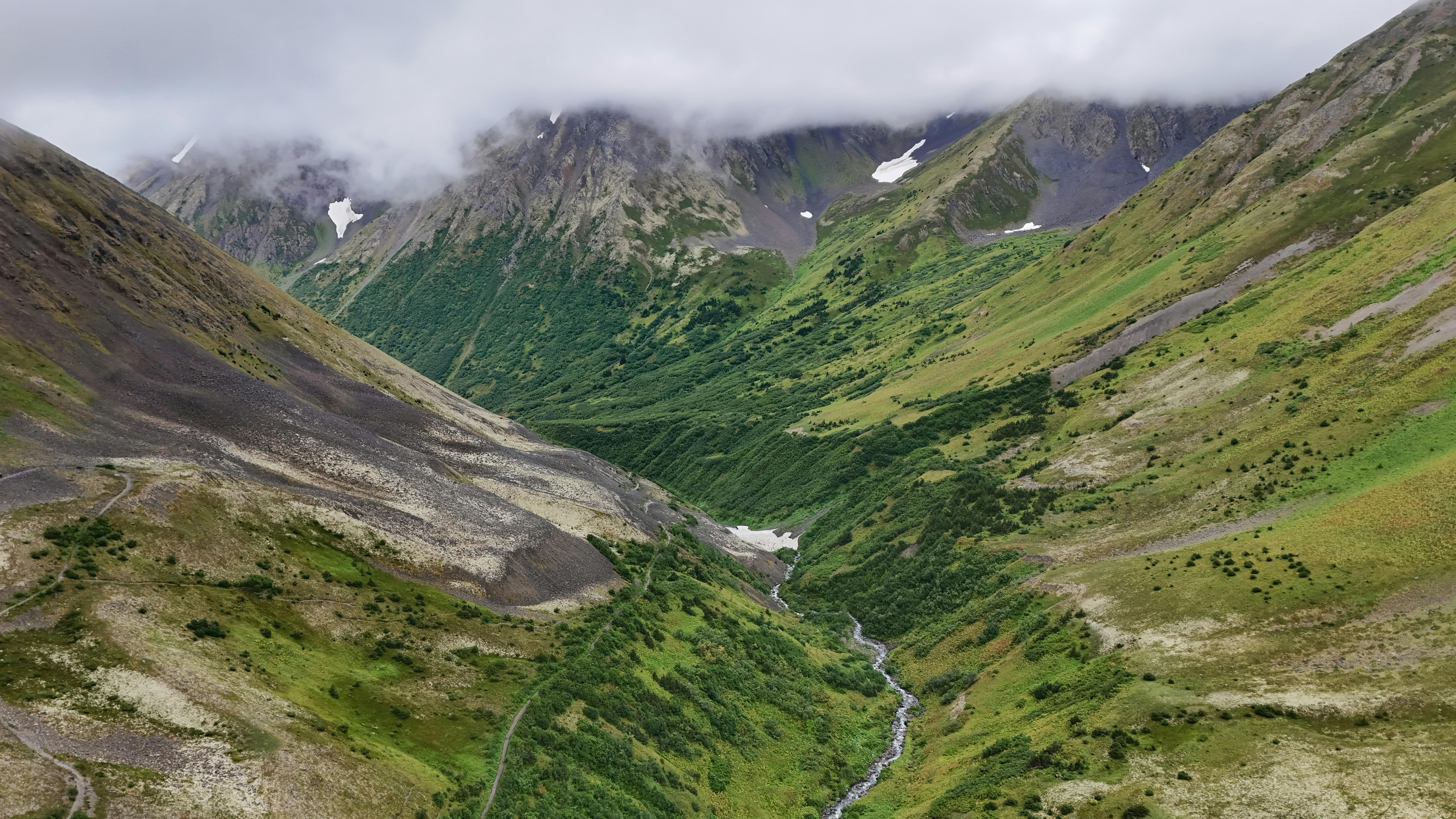 Gratis Vista mozzafiato sulla lussureggiante valle montana verde con cime coperte di nuvole. Foto a disposizione