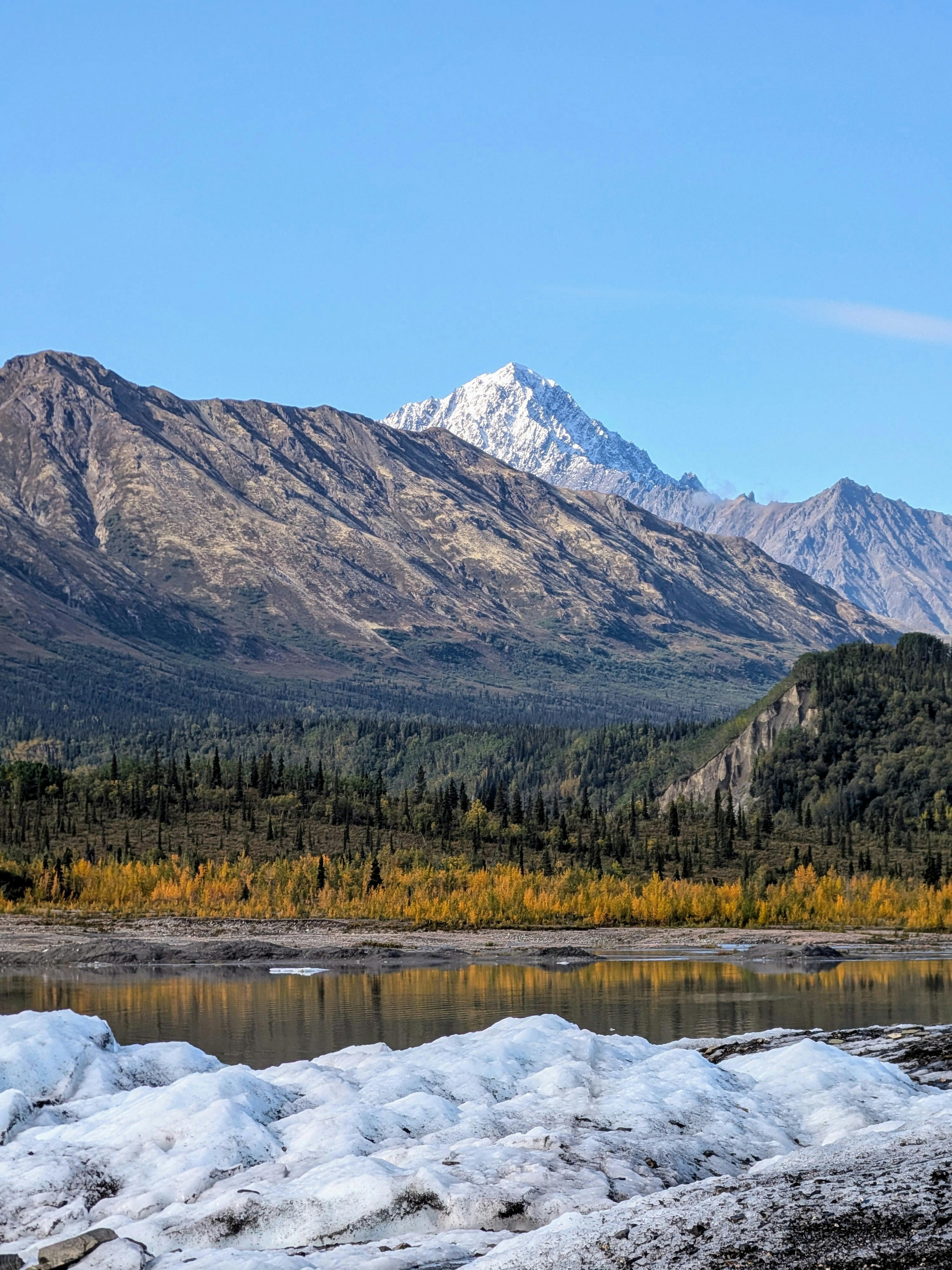Stunning view of a snow-capped mountain with autumn foliage and a serene lake.