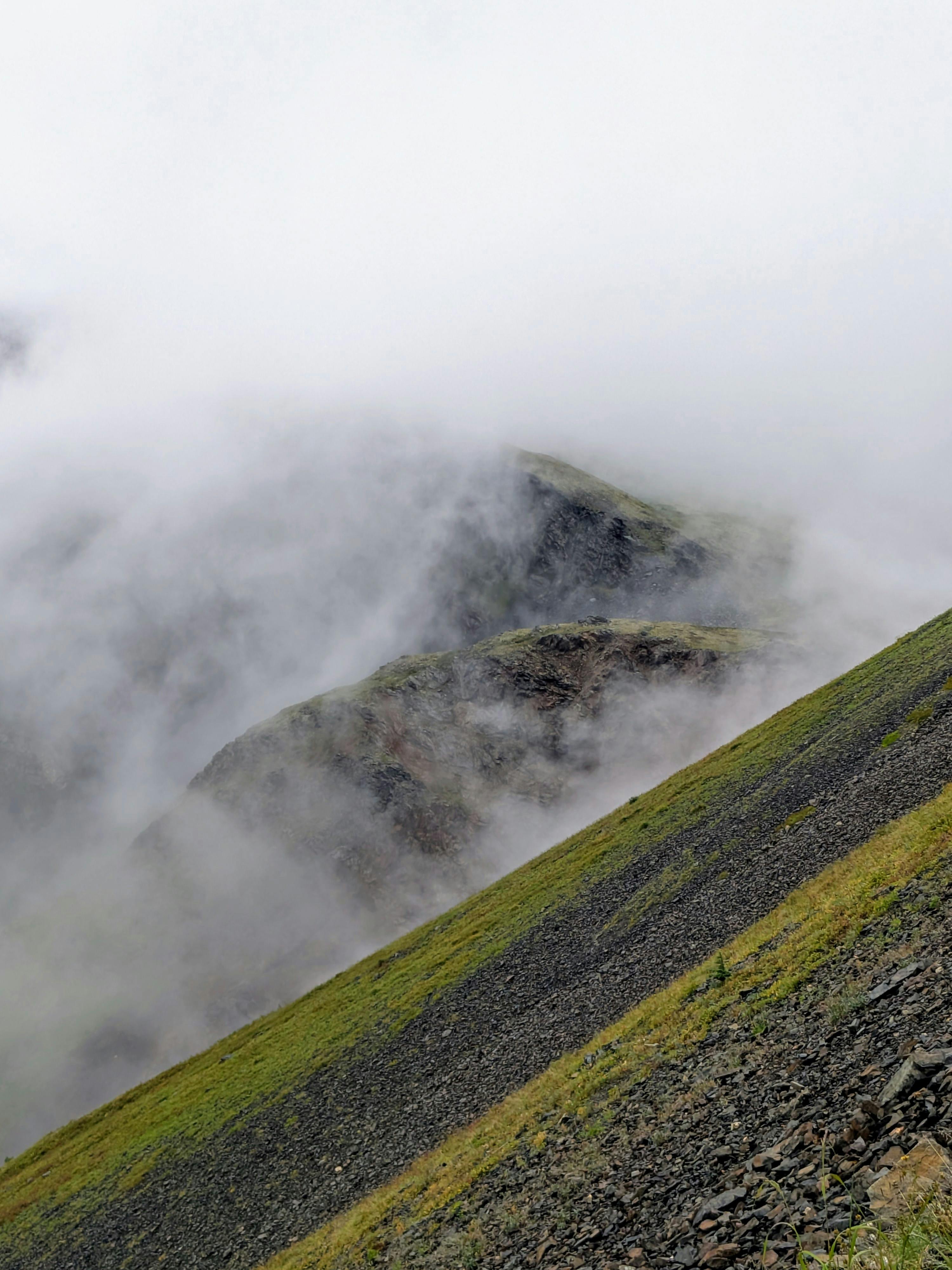 A mist-covered mountain range with lush greenery creating a serene and dramatic scene.