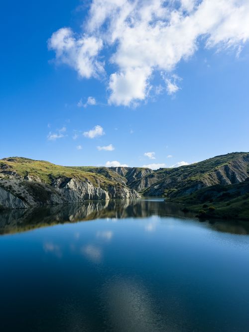 Free Stunning view of mountains reflecting in a calm lake under a clear blue sky. Stock Photo