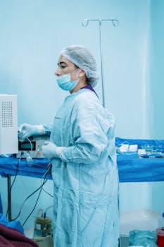 A nurse in surgical scrubs preparing medical equipment in a sterile hospital environment.