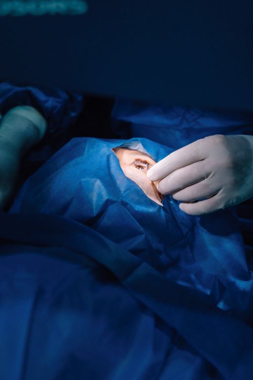 Free A surgeon's hand performing a procedure on a patient's eye in a sterile operating room environment. Stock Photo