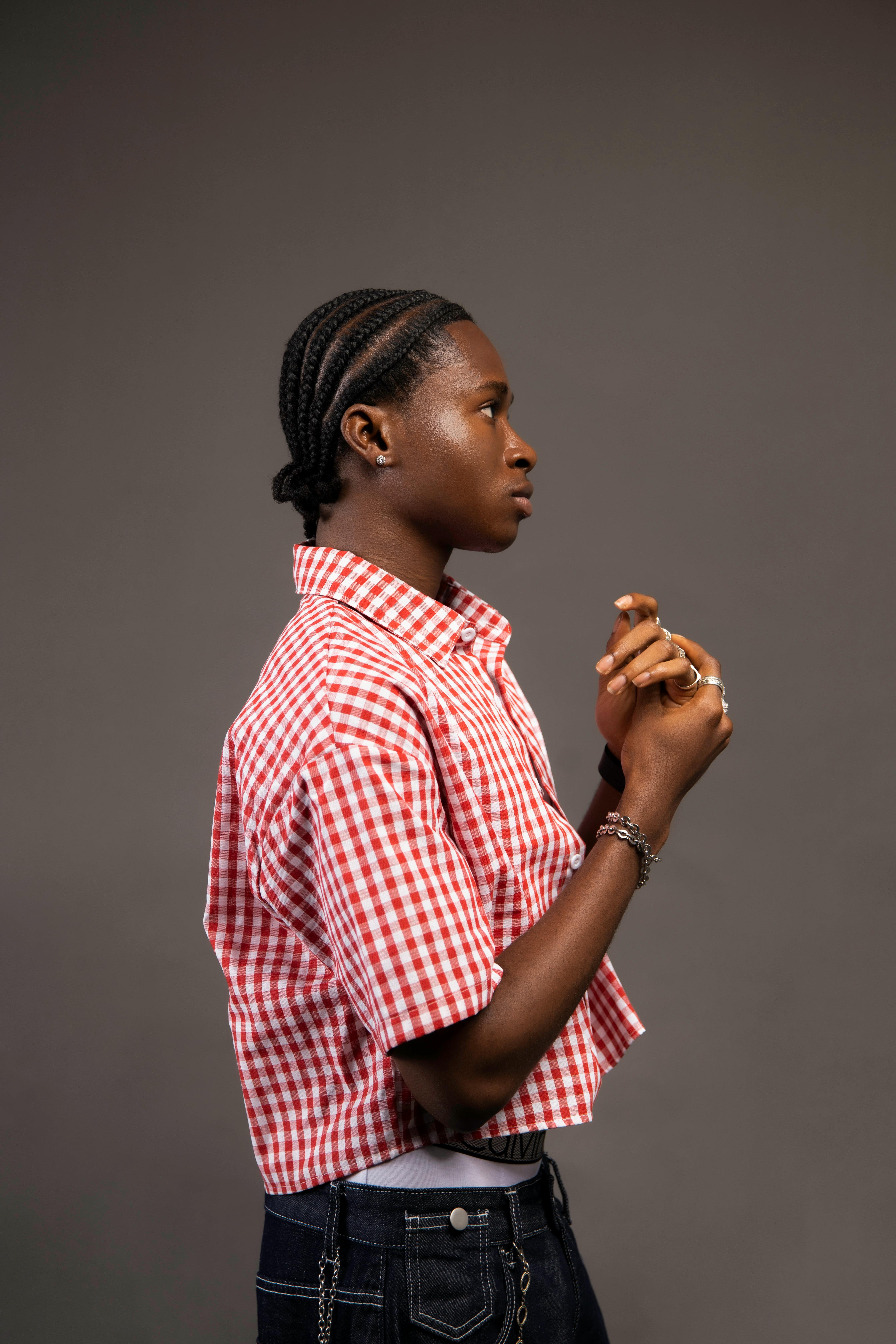 Profile portrait of a stylish young adult in a red checkered shirt, showcasing contemporary fashion.