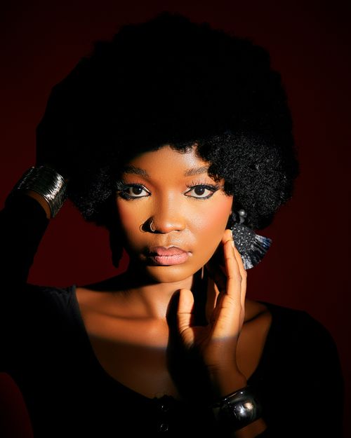 Free Portrait of an adult woman with afro hairstyle, bold makeup, and stylish jewelry. Stock Photo