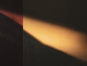 温暖的阳光在纹理墙壁上投下艺术感的阴影，营造出极简而抽象的氛围