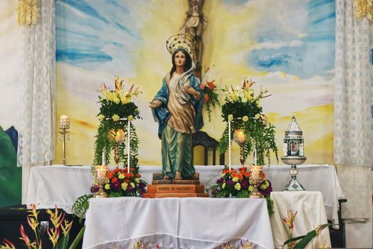 Stunning altar scene featuring a Virgin Mary statue adorned with flowers and candles in a church setting.