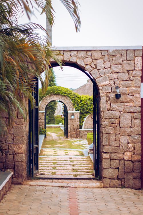 Free Explore a tranquil garden pathway adorned with rustic stone archways and lush greenery. Stock Photo