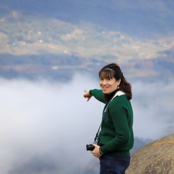 Woman pointing at sea of clouds in Lào Cai, Vietnam, during winter season hike.