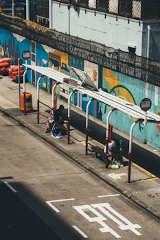 A vibrant urban bus stop featuring colorful street art with individuals waiting in the day.