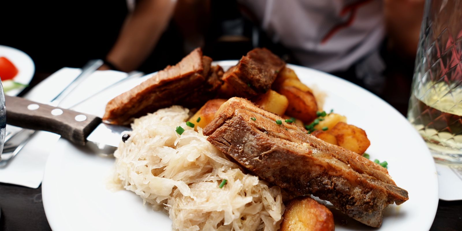 A plate of roast pork, sauerkraut and potatoes served in a cozy setting