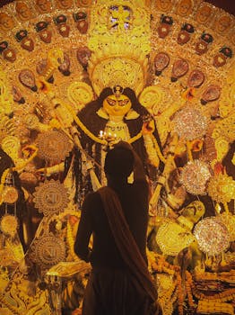 A devotee performing aarti to a beautifully adorned Durga idol during Durga Puja in Kolkata.