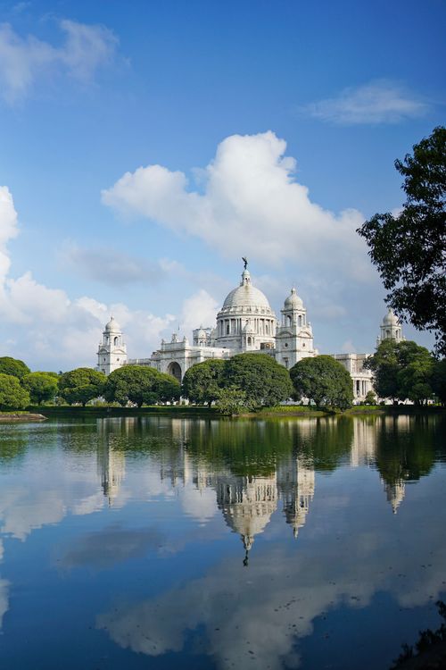 Free Stunning view of the Victoria Memorial reflecting in a serene lake under a clear blue sky. Stock Photo
