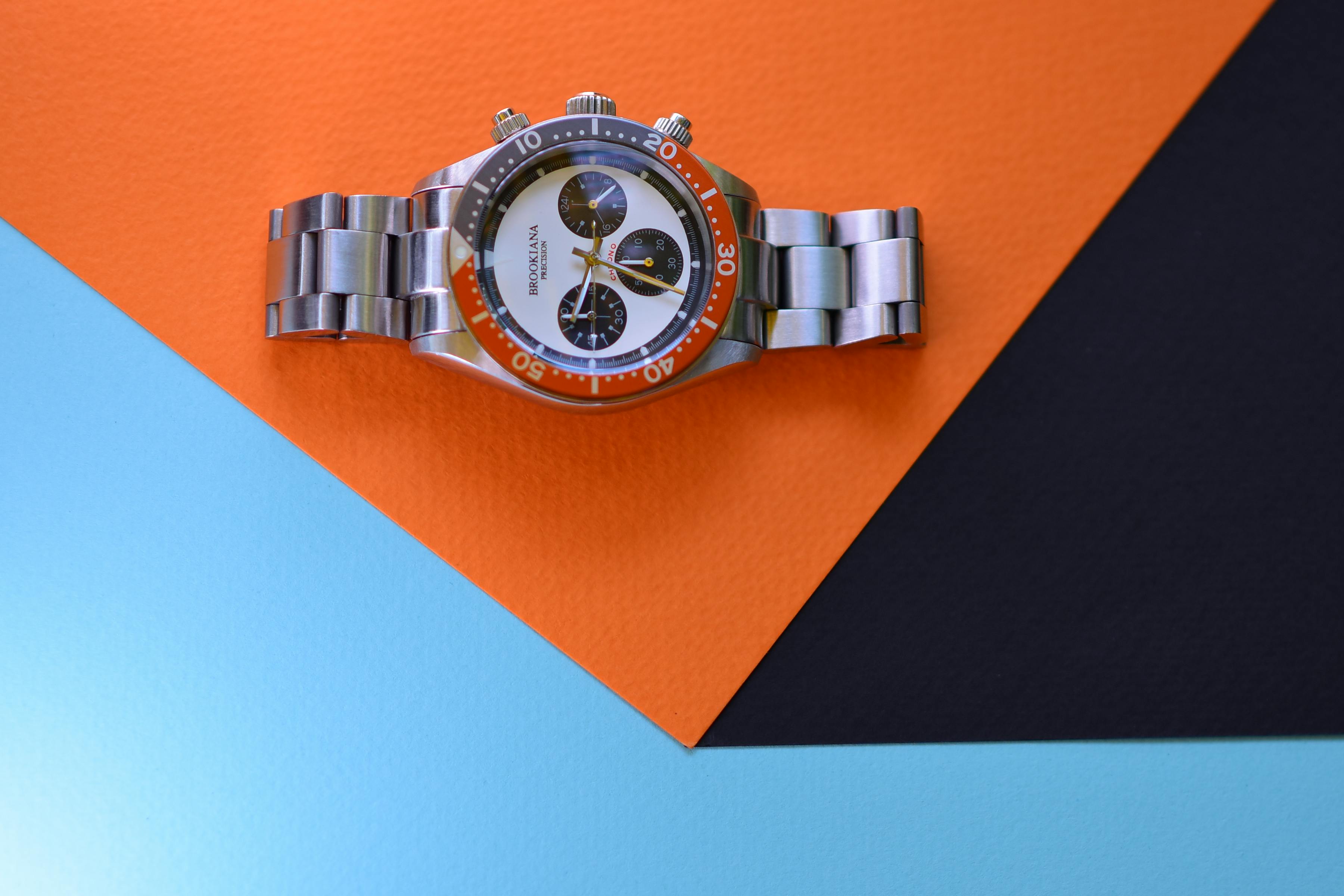 Silver luxury watch displayed on a colorful geometric background highlighting design and elegance.