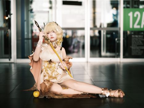 Cosplayer in an elegant fantasy costume sitting indoors, embracing fantasy themes.