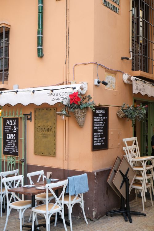 Free Charming corner café in Málaga with empty tables and chairs under a Spanish awning. Stock Photo