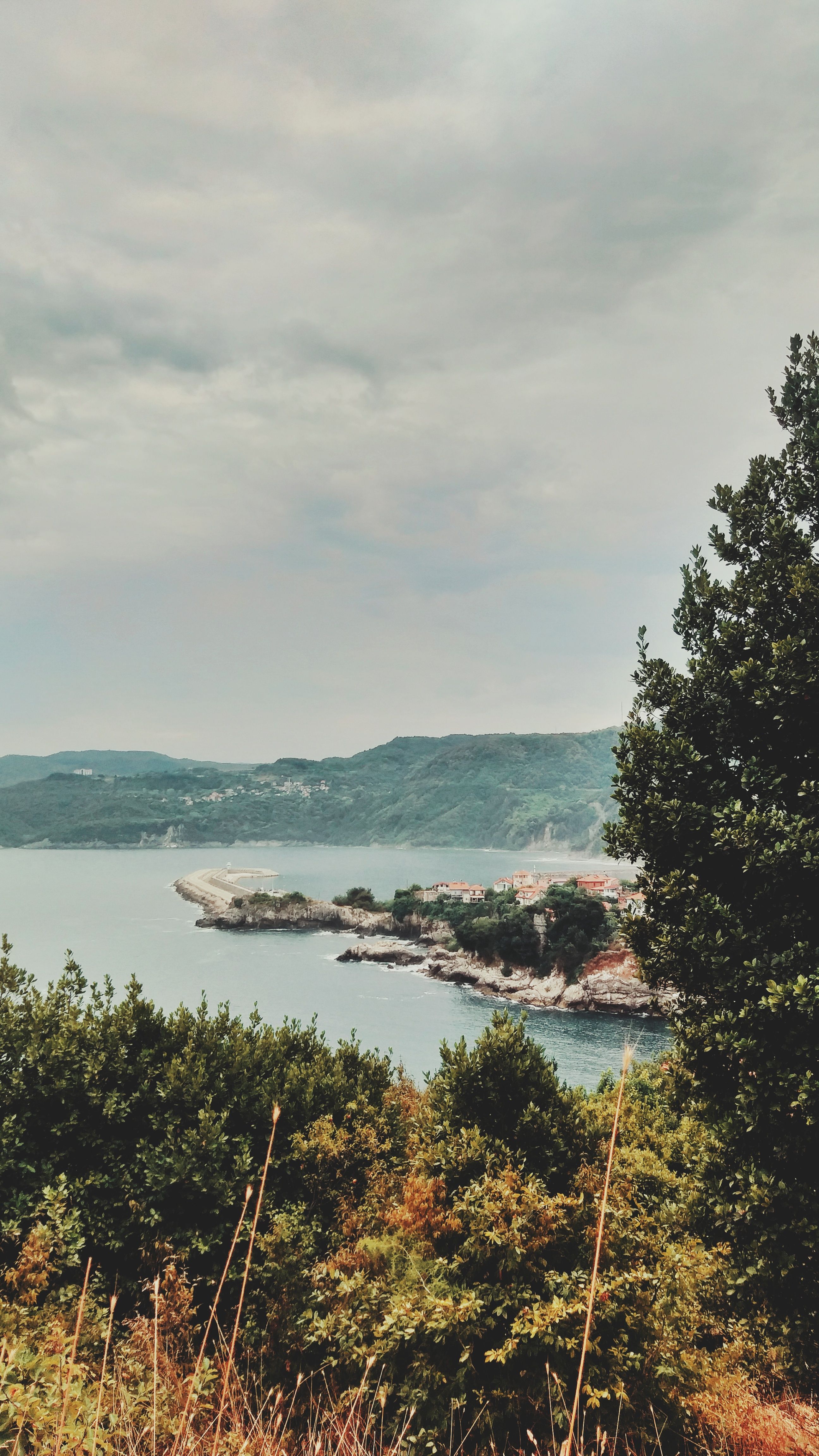 Beautiful view of Amasra's rocky coastline and lush greenery under a cloudy sky.