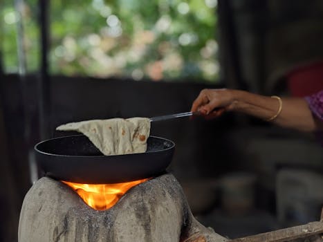 Homemade flatbread being prepared on open flame stove, capturing rustic cooking method.